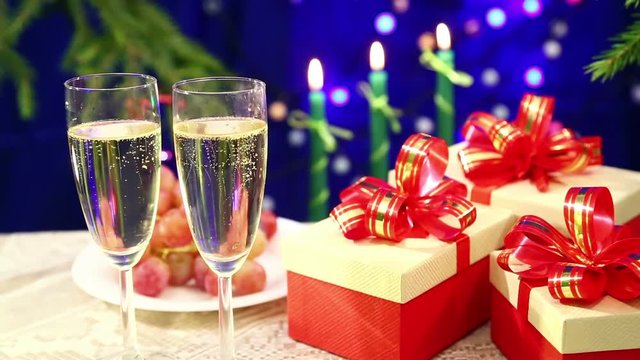 Two glasses of champagne with bubbles close-up against the background of a table with fruit and burning candles and herders blurry bokeh