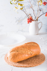 Fresh baguette with bran on a cork substrate on a white table. Crisp bread ready to eat