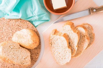 Sliced baguette with bran on a cutting board on the kitchen table. Bread ready to eat. Top view