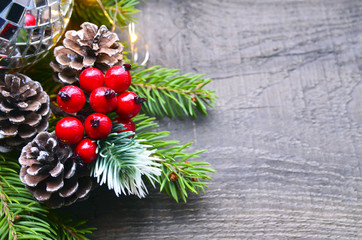 Christmas decoration with fir tree,red berries,garland lights and pine cones on old wooden background.Winter holidays,Merry Christmas,Happy New Year concept. Copy space.Selective focus.