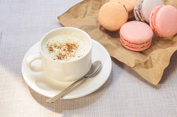 Cake macaroon on the plate,cinnamon and a frothy coffee close up