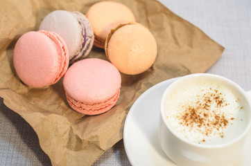 Cake macaroon on the plate,cinnamon and a frothy coffee close up