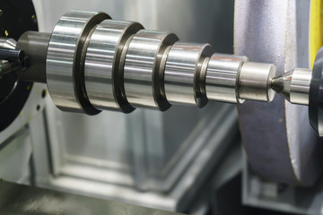 The cylindrical grinding machine with the steel shaft.Hi precision manufacturing concept.