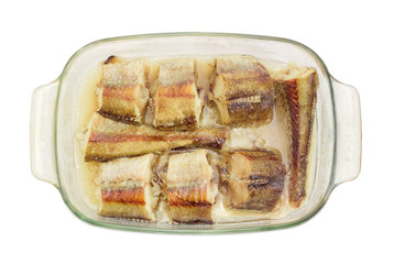 Baked pieces of hake in glass casserole pan closeup