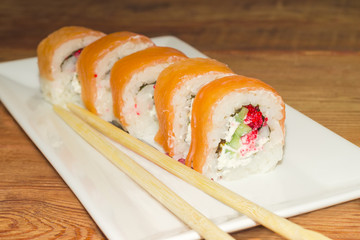 Sushi with salmon with chopsticks on rectangular dish closeup