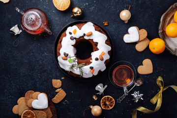 Traditional christmas cake with dried fruits soaked in rum and sugar glaze. Teatime with heart-shaped ginger cookies. Christmas background with festive decoration. Horizontal composition
