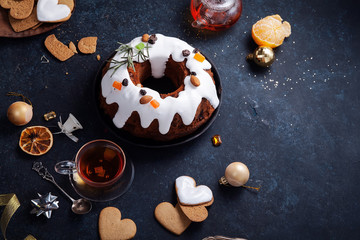 Obraz na płótnie Canvas Traditional christmas cake with dried fruits soaked in rum and sugar glaze. Teatime with heart-shaped ginger cookies. Christmas background with festive decoration. Horizontal composition