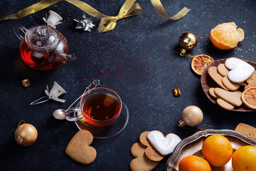 Fototapeta na wymiar Teatime with heart-shaped ginger cookies and tangerines. Christmas background with festive decoration. Horizontal composition