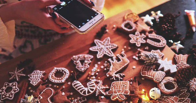 Woman Taking Pictures of Gingerbread Cookies Flat Lay. 4K SLOW MOTION. Christmas Holiday  bakery, advent traditions. Female hands using smartphone, making food pictures for social media, using app. 