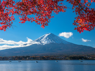 Fuji mountain with red maple and the fishermen are fishing on boat in the lake.