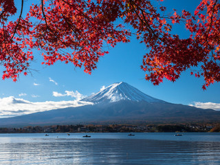 Fuji mountain with red maple and the fishermen are fishing on boat in the lake.