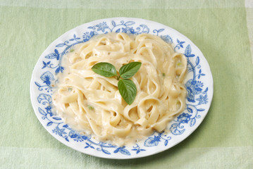 Pasta with mix vegetable and white sauce on the brown wood table 