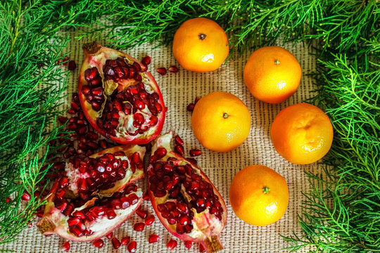 Pomegranate, grains of pomegranate, mandarins near the branches of the Christmas tree.New year concept. Flat lay. Top view