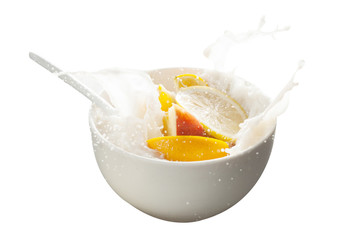 Pouring milk into bowl with fruits and splashes isolated with white background