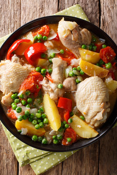 Filipino Afritada: slices of chicken with vegetables close-up in a bowl. Vertical top view