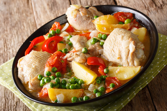 Pieces of chicken stew with potatoes, peppers, tomatoes, peas and onions close-up. horizontal