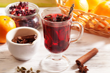 Mulled wine Karkade tea, with a badge and cardamom in a glass on a wooden table top orange