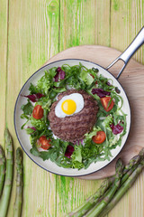 Cutlet with egg in a frying pan with vegetable garnish top