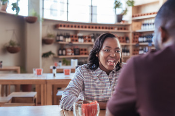 Young African woman laughing with her date in a cafe