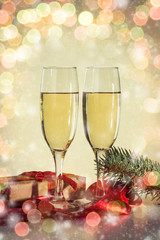 Two glasses with champagne and a packed gift. Bokeh
