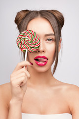 Beauty fashion model with colourful lollipops. Young pretty woman with pink lips and makeup. Candies like a sunglasses
