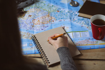 Fototapeta na wymiar Travel concept. Girl writes to a notebook on the background of a map