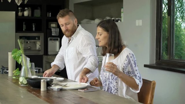 Couple talking and cleaning table after breakfast in kitchen at home 
