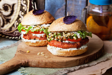 Vegetarian burger with chickpea chop and germinated mush in a still life on a wooden table close-up home food