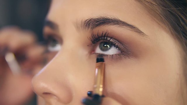 Closeup view of professional makeup artist's hands using makeup brush to apply eye shadows. Slowmotion shot