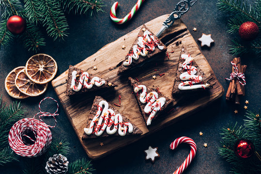 Chocolate brownies with candy canes and Christmas decorations on dark background. Top view. Toned image