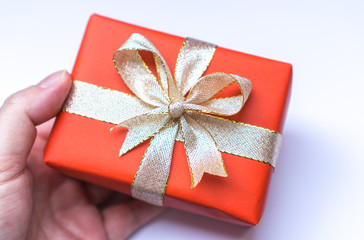 Red wrapped gift with golden ribbon holding in hand