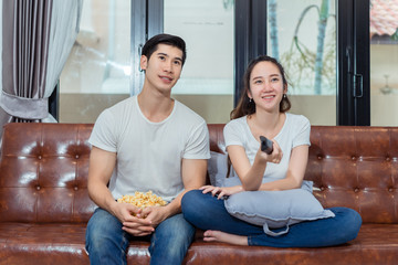 Obraz premium Couple together watching television funny reaction on sofa in living room at room