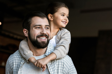 Obraz premium cheerful father and daughter hugging and looking at side. at home