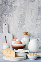 Dairy products on marble table over concrete background. Cheese, farmers cheese, milk, yogurt, sour cream, eggs and smoked cheese. Organic farmers dairy products