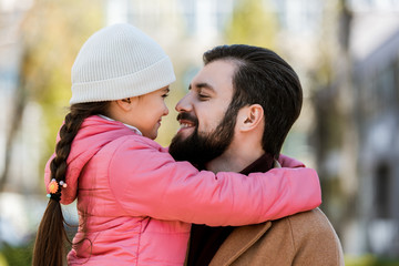 happy father with daughter hugging in autumn outfit and looking at each other. outside