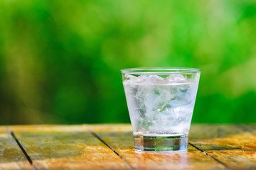 A glass of water with ice on green background