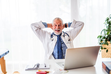 Fototapeta premium Senior doctor with laptop at the office desk.