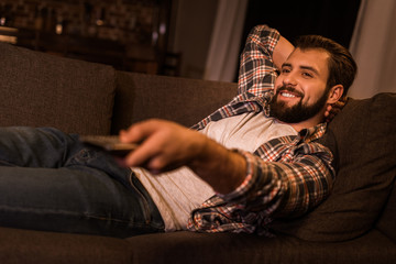 Obraz premium young man laying on couch and watching tv at home