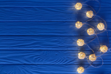 christmas garland lights on blue wooden background with copy space for your text. Top view