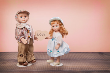 Valentine's day vintage card. Toys of boy and girl with cardboard heart with the inscription love.