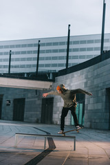 professional skateboarder balancing with board on bench in urban location