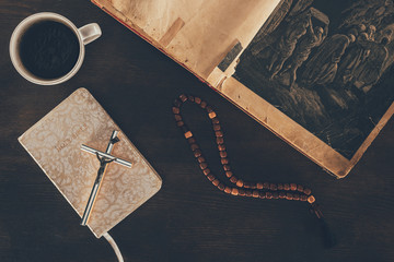 top view of open bible and rosary on wooden table