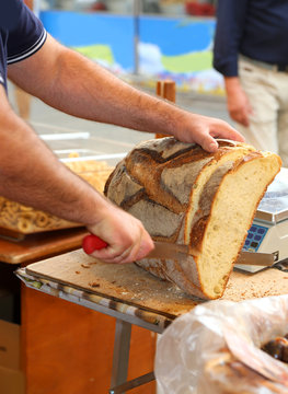 baker cuts a large loaf of baked bread into the bakery