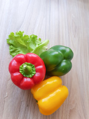 Green, Yellow, Red sweet bell pepper on wood table background.