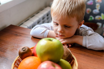 Fototapeta premium The child looks for fruit and smiles.