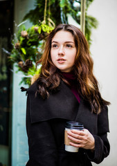 Brunette woman with long hair drinks coffee at the table