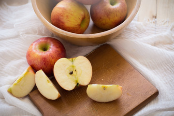 Red apples in a wooden bowl on a wooden background