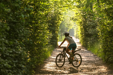 Fototapeta na wymiar Woman rides bicycle in the beautiful green forest