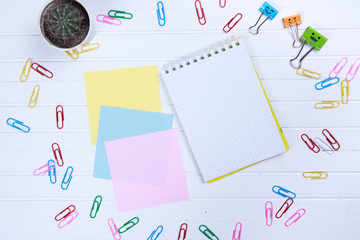 note paper and note book with paper clips on white wooden background