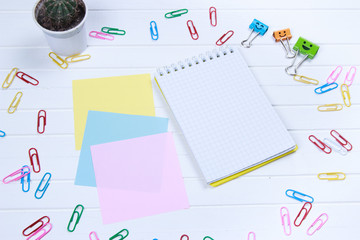 note paper and note book with paper clips on white wooden background